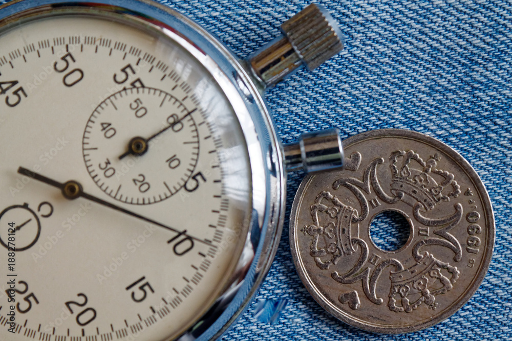 Denmark coin with a denomination of five crown (krone) (back side) and stopwatch on worn blue jeans backdrop - business background