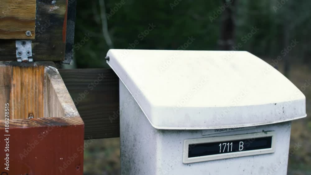 Old mailbox in the forrest being oppened by a hand, that then deliveres a newspaper and closes the lid again