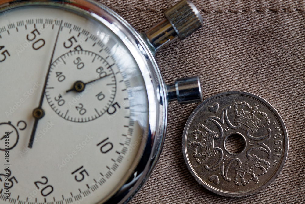 Denmark coin with a denomination of two crown (krone) (back side) and stopwatch on worn beige denim backdrop - business background