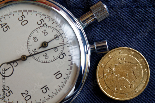 Euro coin with a denomination of fifity euro cents (back side) and stopwatch on worn blue jeans backdrop - business background photo