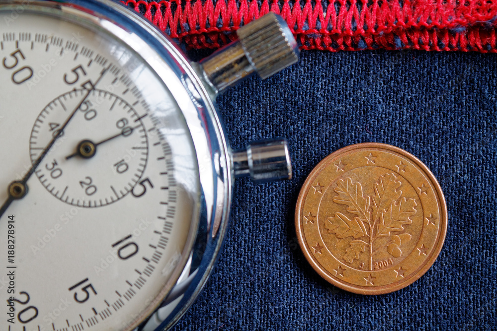 Euro coin with a denomination of five euro cents (back side) and stopwatch on worn blue denim with red stripe backdrop - business background