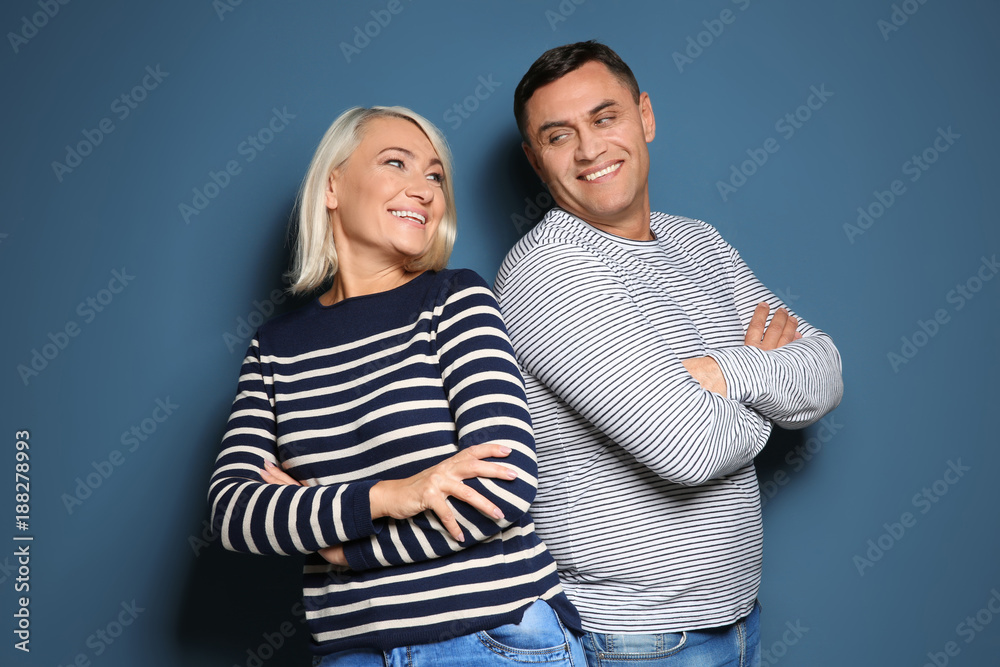 Cute middle-aged couple on color background