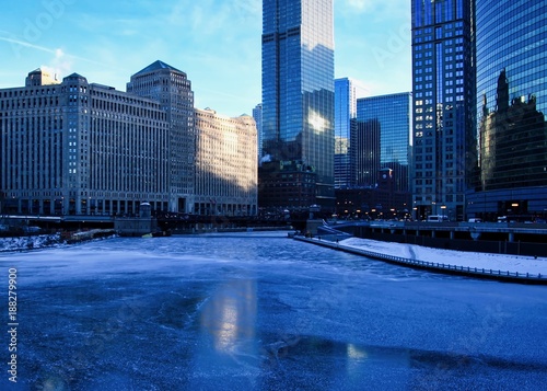 Frigid, blue morning in Chicago during January freeze with view of a frozen river near Merchandise Mart building.