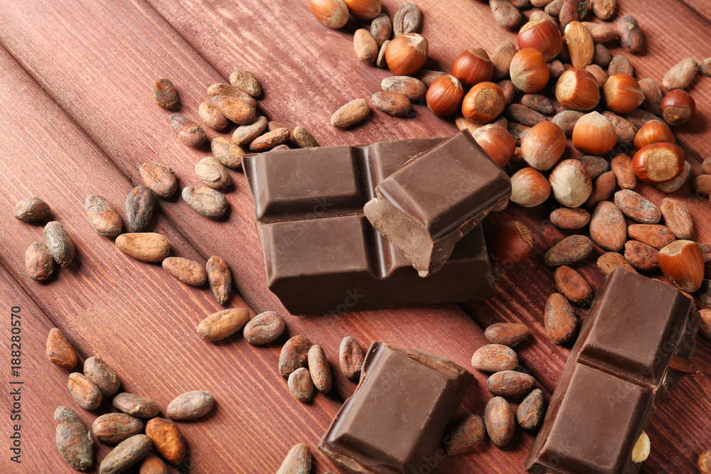 Chocolate pieces, hazelnuts and cocoa beans on wooden background