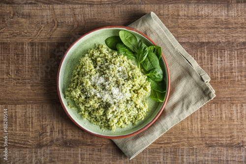 Plate with delicious spinach risotto on wooden table