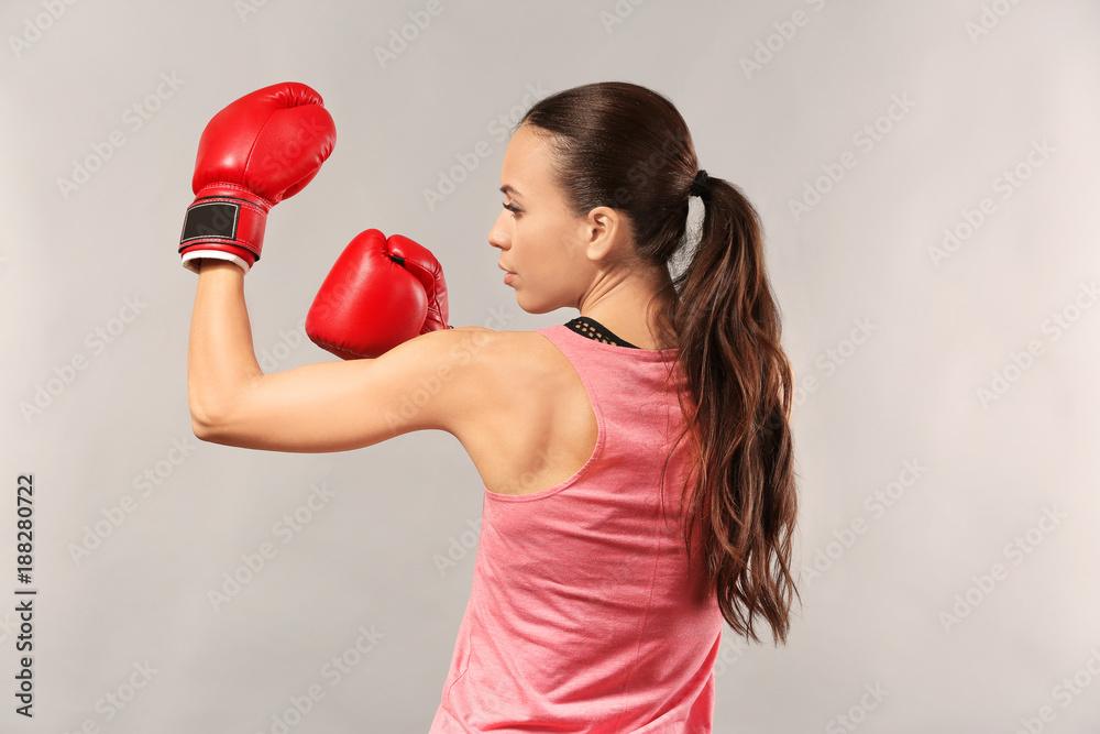 Strong woman in boxing gloves on grey background Strong woman in boxing gloves on grey background