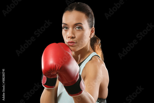 Strong woman in boxing gloves on black background © Africa Studio