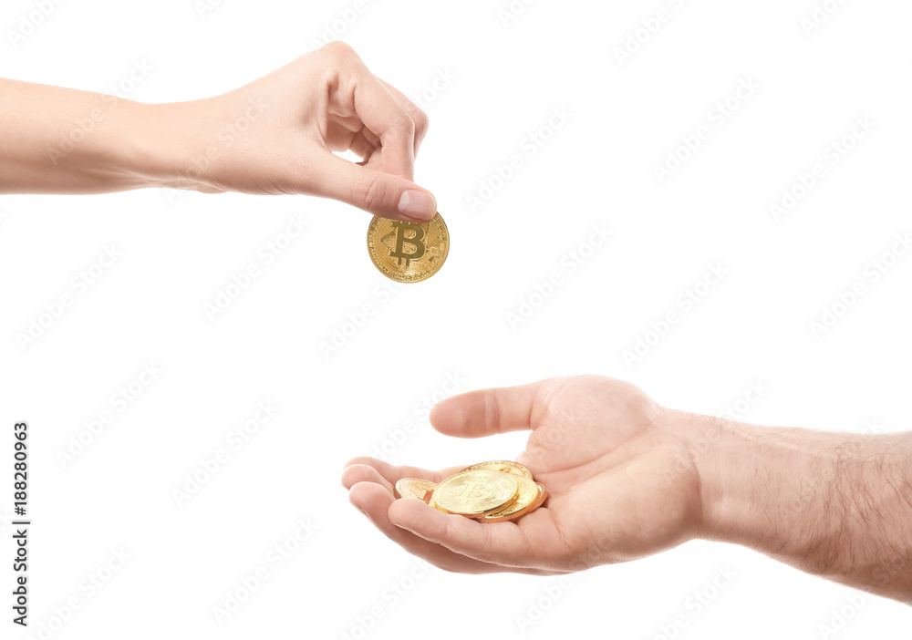 Hand of woman putting golden bitcoin on man's palm against white background Hand of woman putting golden bitcoin on man's palm against white background