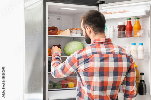 Man choosing food in refrigerator at home