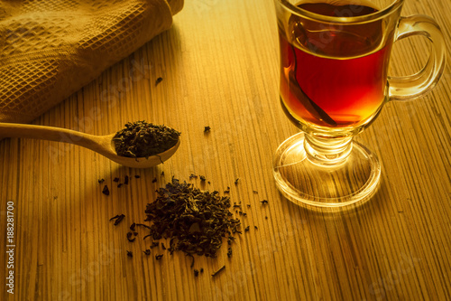 Brewing tea, spoon with tea leaves and cup of tea photo