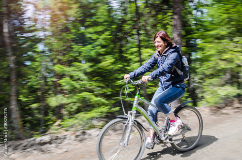 Woman Riding a Bicycle on a Mountain Road on a Sunny Spring Day. Blurred Motion. © alpegor