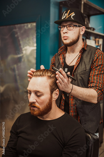 A man visits a hairdresser. The hairdresser does a hairstyle to a man. Hipster in the hairdresser