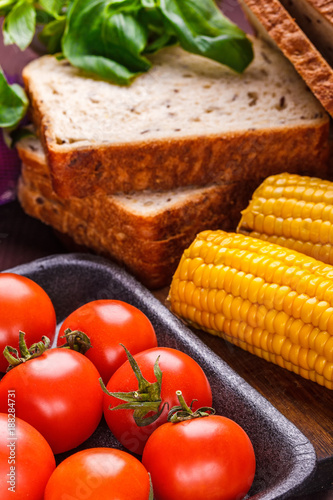 A set of products for a quick lunch: tomatoes, corn, bread, basil