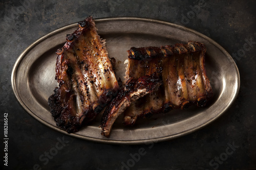 Grilled pork spare ribs cooked with balsamic vinegar and honey sauce on vintage metallic tray. Dark rustic background. photo