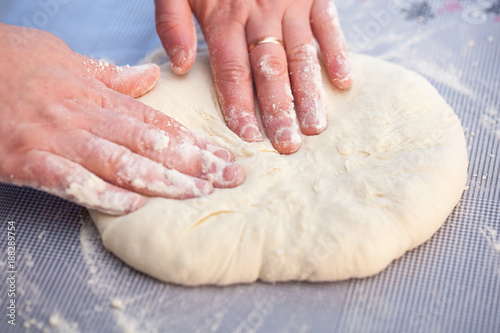 Baker hands preparing khachapuri on kitchen table. View on cook making traditional georgian treat with raw dough