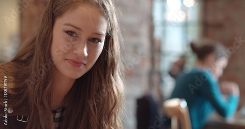 Portrait of young beautiful girl smiling to a camera while sitting at restaurant. 