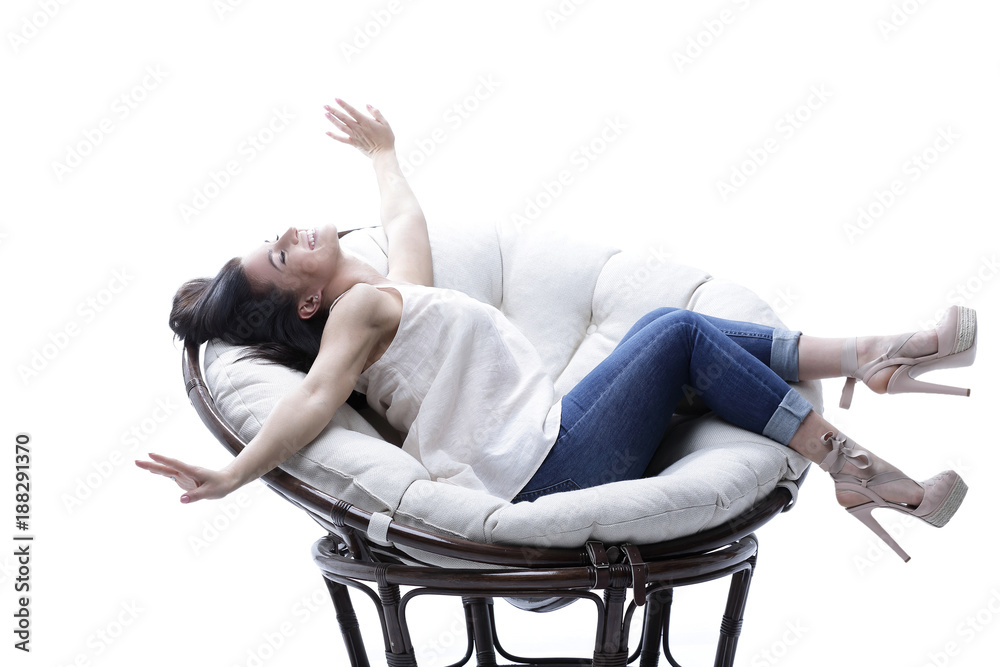 Modern young woman relaxing in a round cozy soft chair