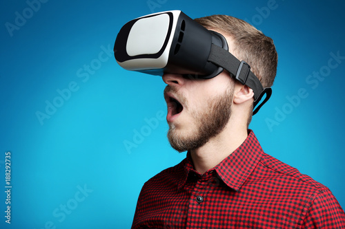 Young man in virtual reality goggles on blue background © 5second