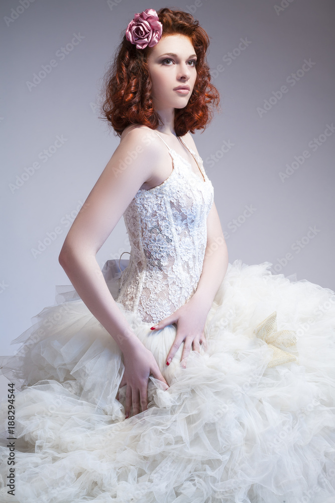 Wedding Ideas and Concepts. Young Caucasian Ginger Female Wearing Tailored Wedding Dress. Posing Against Gray Background. Wedding Ideas and Concepts. Young Caucasian Ginger Female Wearing Tailored Wedding Dress. Posing Against Gray Background.