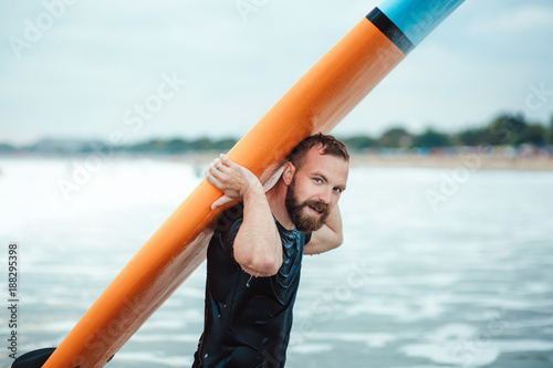 Canvas Print A man is a surfing man carrying his surf boards near the shore on a sunny golden day on vacation