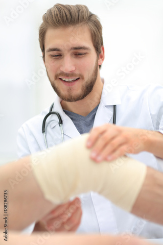 traumatologist examining the bandage on his knee.