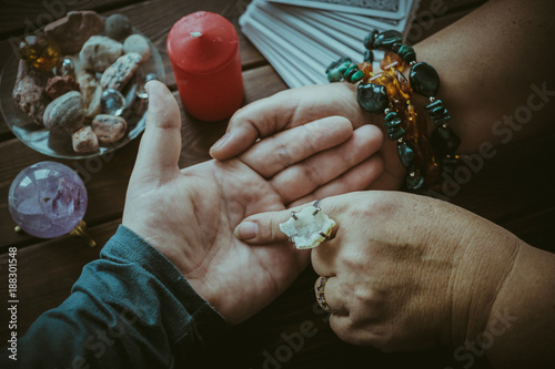 Witch or fortune teller reading fortune lines on male palm or hand
