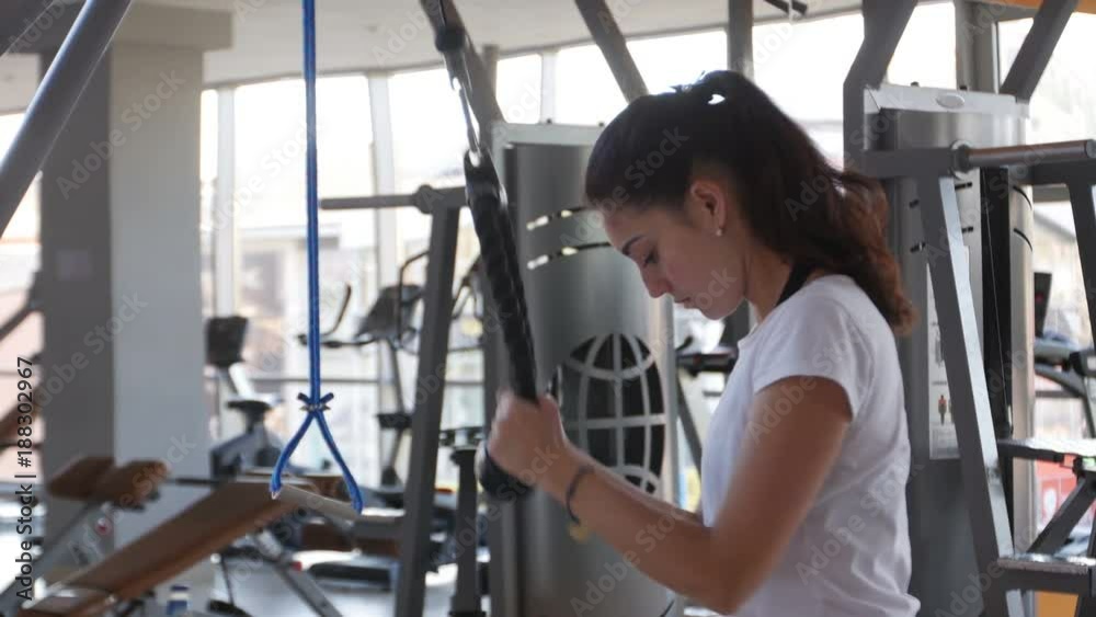 young girl trains the triceps muscles on the equipment in the gym young girl trains the triceps muscles on the equipment in the gym