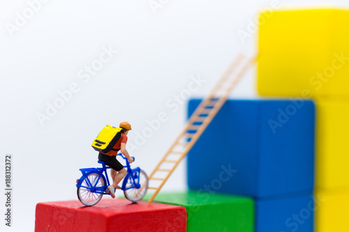 Miniature people : Traveler use the bicycle with takes the ladder from one place to another. Image use for travel, business concept.