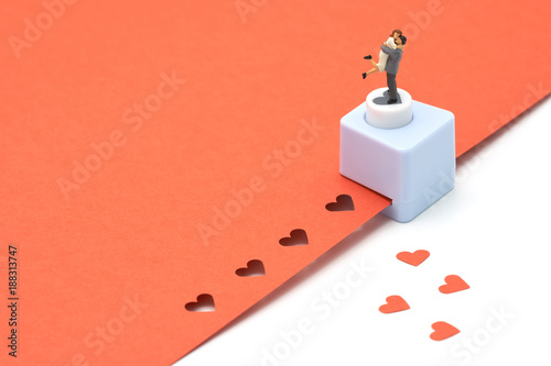 couple Miniature 2 people standing with Heart shaped punching machine Punch red paper Red heart is the promise of love.  as background Valentine concept with copy spaces for your text or design. photo