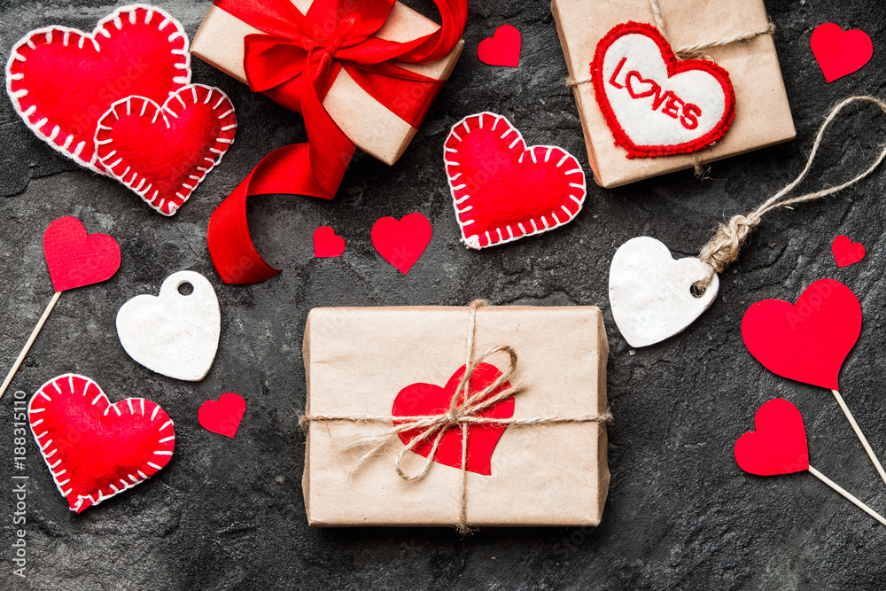 Valentines day background. Red hearts, ribbon and gift box on concrete background.