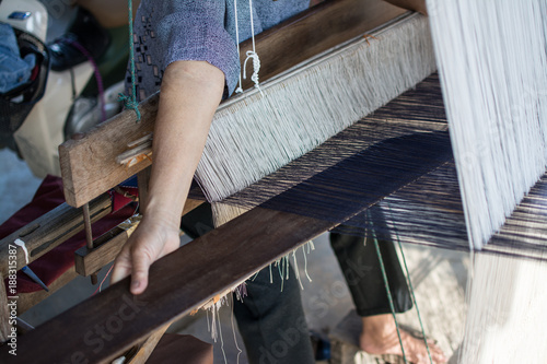 Woman weaving silk in traditional way at manual loom. Thailand