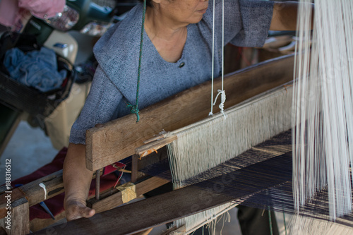 Woman weaving silk in traditional way at manual loom. Thailand