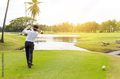 young asian businessman playing golf on the beautiful golf course in the morning with sunbeam at summer time.