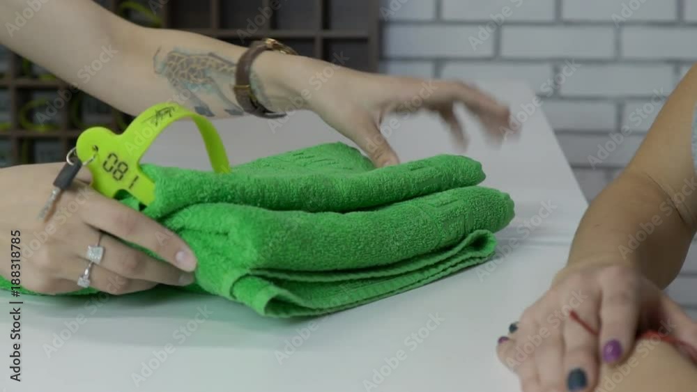 Closeup of cloakroom attendant gives woman towel, keys on and receipt