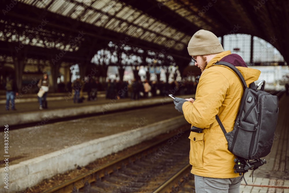 man stands on the railway station look into smartphone