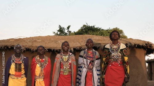 wide shot of five maasai women in traditional dress singing and dancing in a village near maasai mara, kenya photo