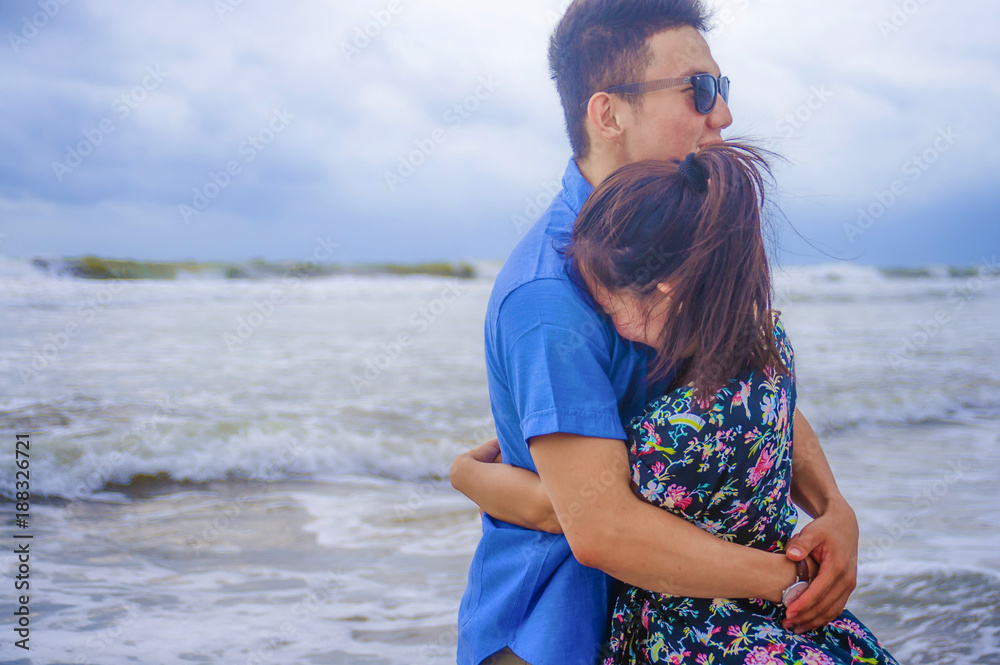 beautiful Chinese Asian couple with woman hug her boyfriend romantic and cuddle on the beach smiling in dating and romance