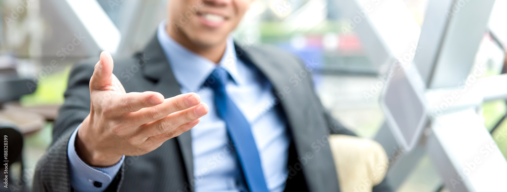 Businessman reaching out hand with open palm, welcome gesture Businessman reaching out hand with open palm, welcome gesture