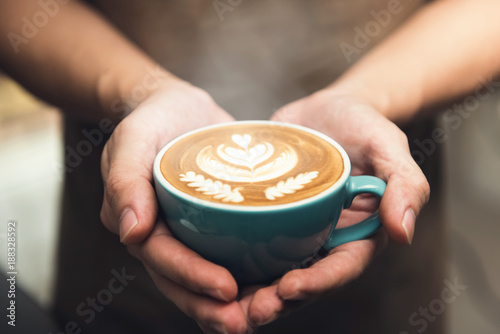 Hands giving a cup of latte art coffee