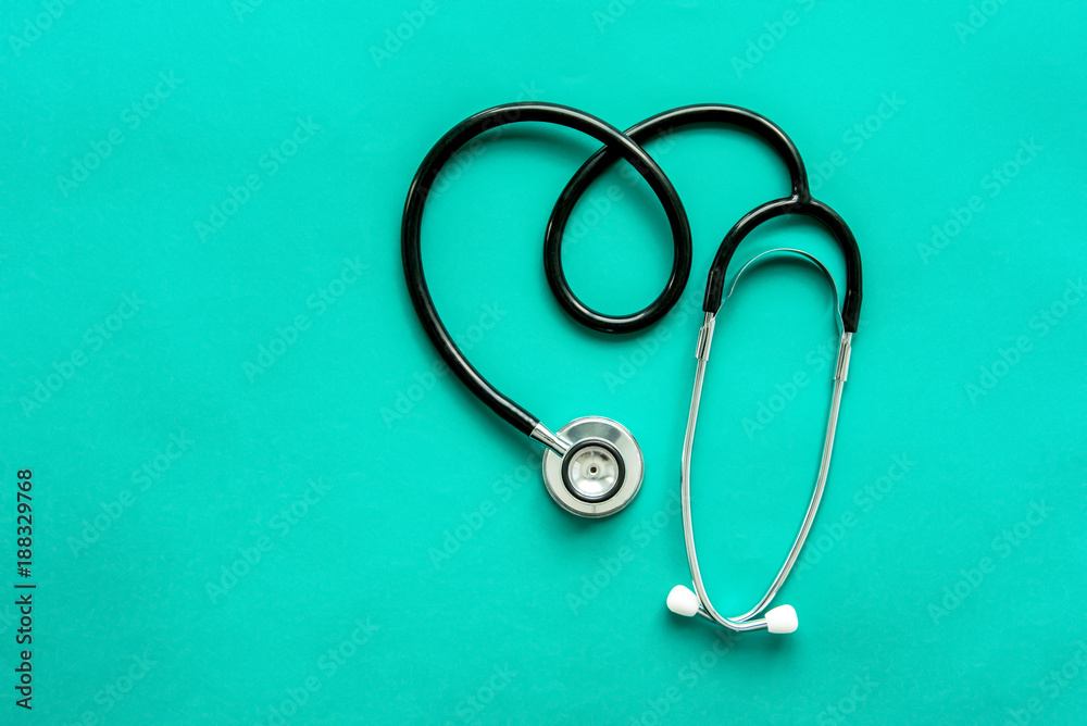 Stethoscope in heart shape on light green background Stethoscope in heart shape on light green background