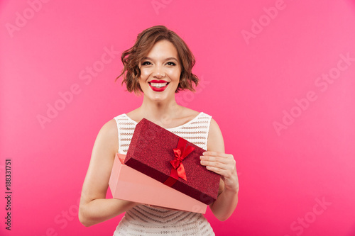 Portrait of a happy girl dressed in dress holding gift box