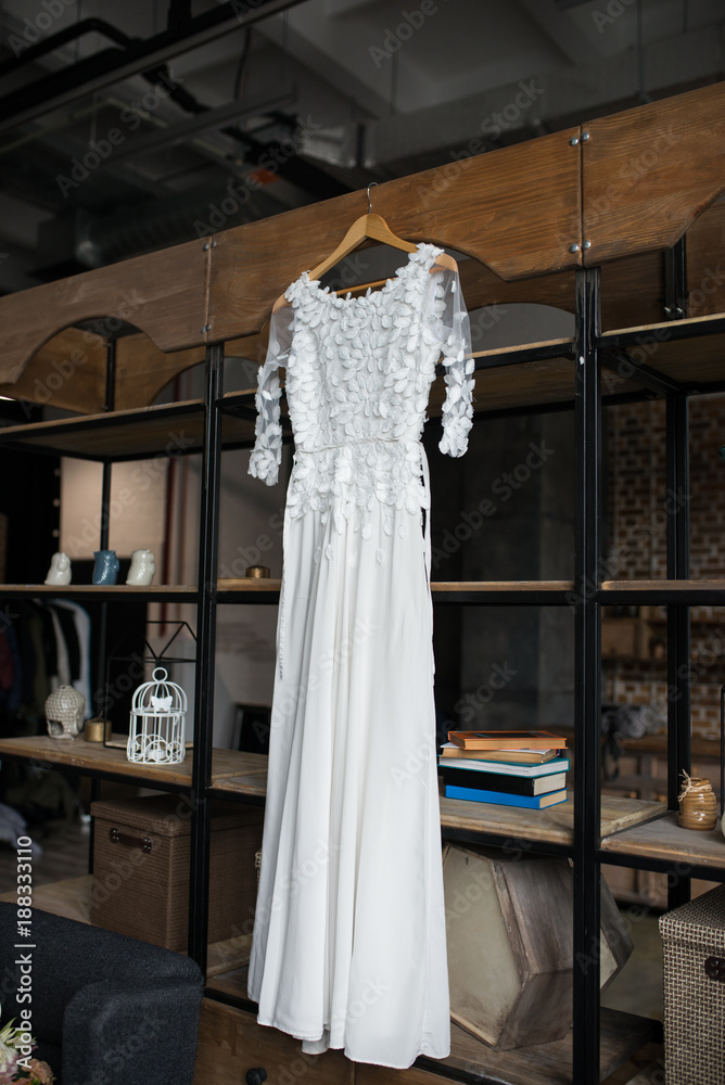 Rustic white wedding dress hanging on the cupboard. Loft interior