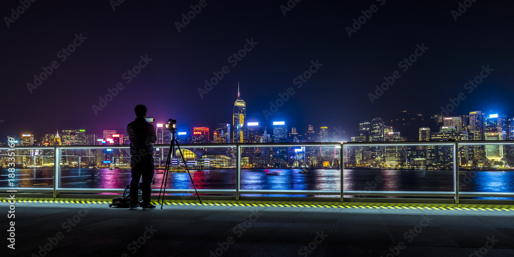 Fototapeta premium Man taking photo for the beautiful night view of Victoria Harbor of Hong Kong