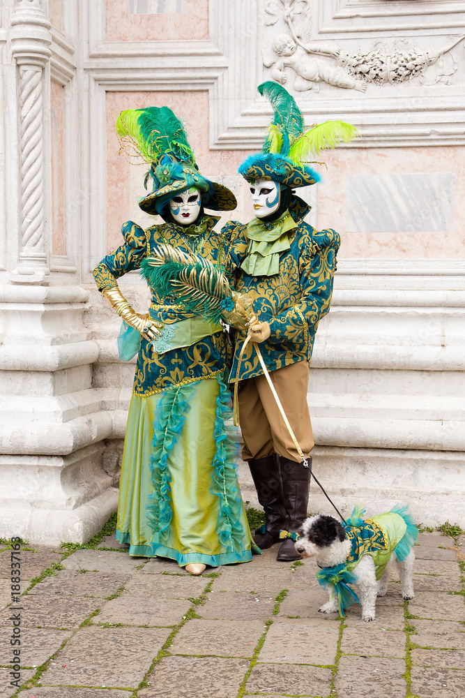 Obraz premium Venetian masks of Lovely Couple with dog on Venice Carnival in colorful and elegant costume San Zaccaria Square - Venice Carnival
