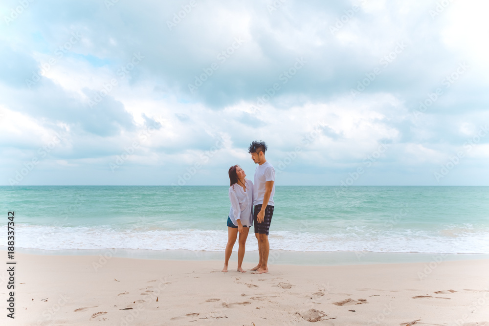 Portrait image of a lover couple looking at each other with feeling loved on the beach , the sea and blue sky background Portrait image of a lover couple looking at each other with feeling loved on the beach , the sea and blue sky background