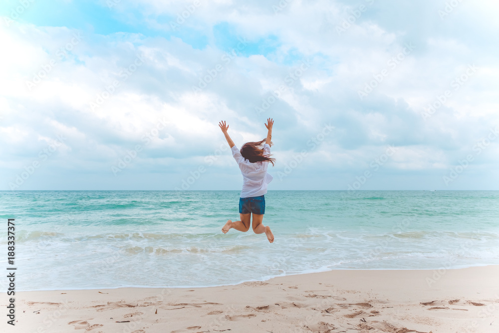 A woman jumping on the beach in front of the sea with feeling happy and freedom A woman jumping on the beach in front of the sea with feeling happy and freedom