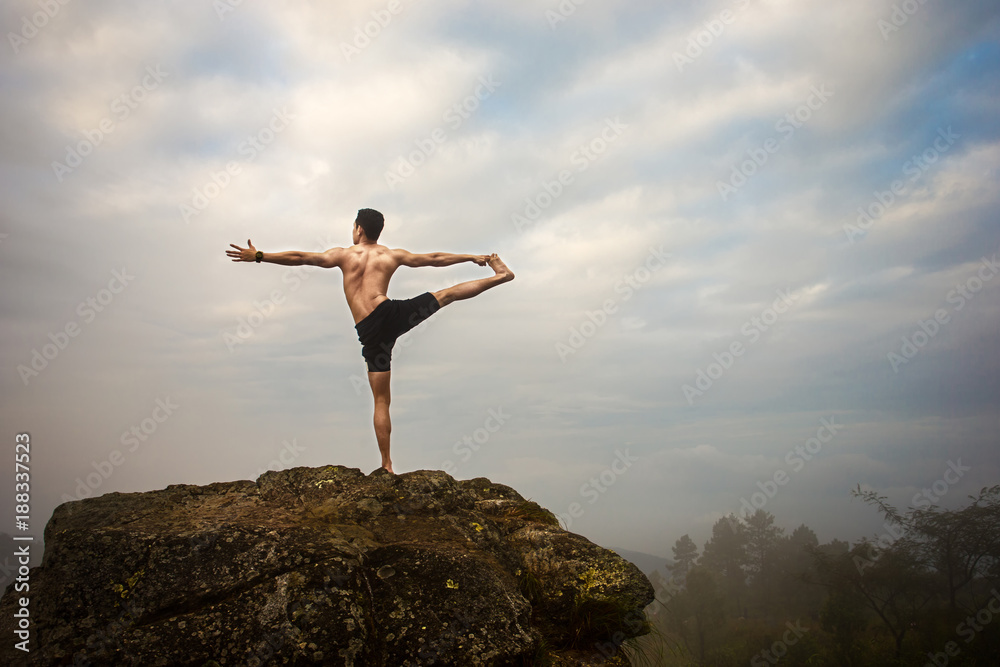 A professional trainer doing yoga on the rock over the sunrise in the morning. A professional trainer doing yoga on the rock over the sunrise in the morning.