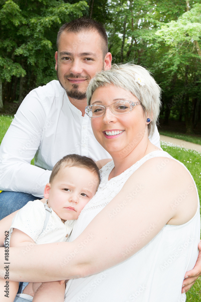 Beautiful pregnant woman with her husband and young son in green garden