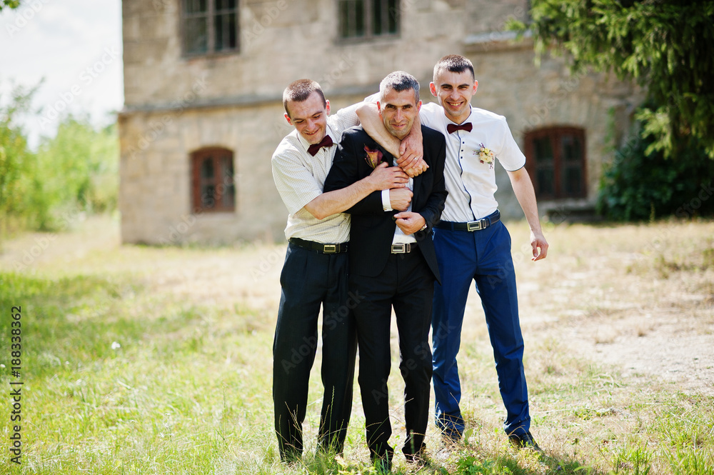 Groom posing with two groomsmen on a sunny wedding day next to the castle. Groom posing with two groomsmen on a sunny wedding day next to the castle.