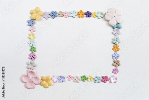 Color paper flower arrange in frame shape on white paper texture background, valentine card concept, greeting card background